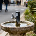 Fontaine à eau sans électricité publique sur trottoir avec robinet et eau coulant