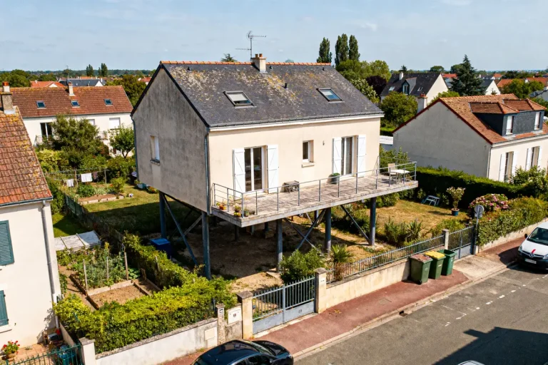 Maison surélevée sur pilotis avec terrasse surplombant le voisinage verdoyant et résidentiel