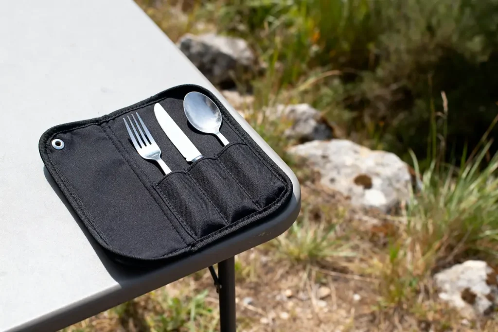 Étui à couverts noir posé sur table en plein air avec fourchette, couteau et cuillère