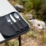 Étui à couverts noir posé sur table en plein air avec fourchette, couteau et cuillère