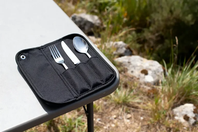 Étui à couverts noir posé sur table en plein air avec fourchette, couteau et cuillère