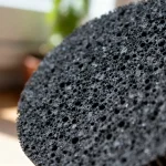 Gros plan sur une mousse noire constituant un filtre en charbon actif poreux.