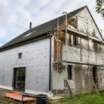 Maison en rénovation avec isolation thermique complète par tousrenov.be et échafaudages visibles.