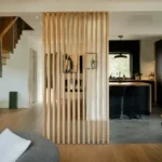 Salon avec meuble de séparation moderne en bois pour tousrenov.be, cuisine visible à droite