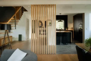 Salon avec meuble de séparation moderne en bois pour tousrenov.be, cuisine visible à droite
